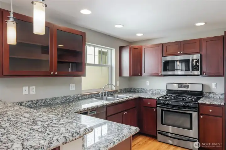 Kitchen with granite slab countertops.  New gas cooking range in 2025