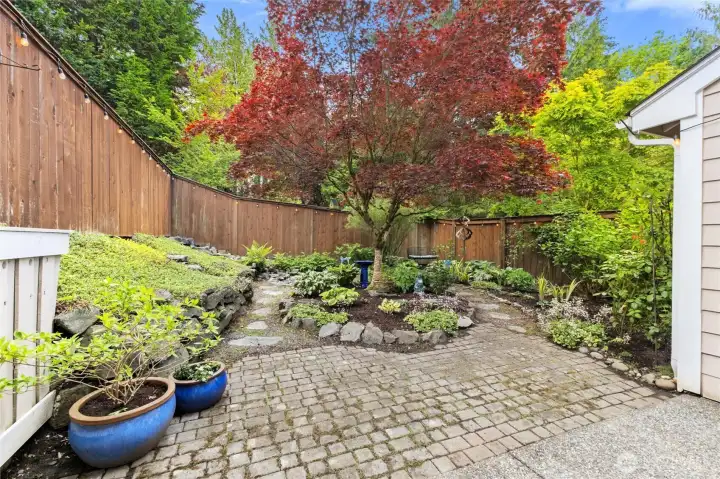 Welcoming Garden & Pebbled Path. Be Sure To Walk Back and Find a Gentle Water Feature & Bricked Bench Area For a Quiet Moment of Rest. Pavers Growing with Minted Ground Coverings and room for BBQ or Lounge Chairs