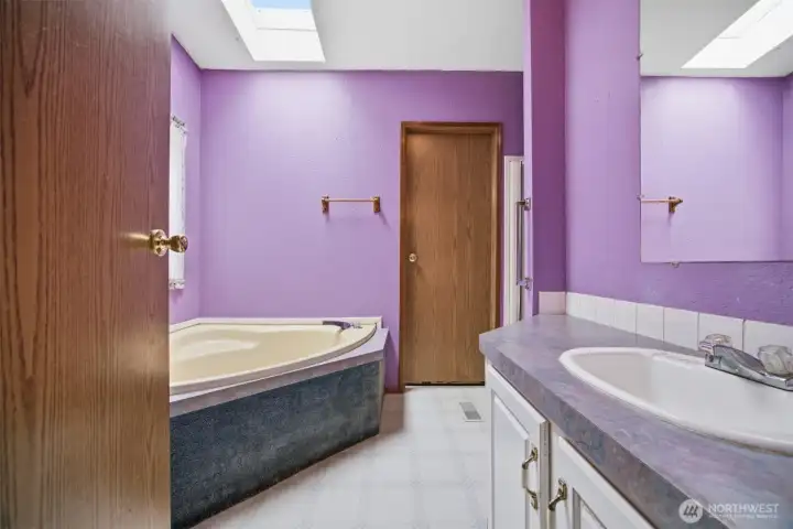 The primary bathroom is between the primary bedroom and the laundry room. There is a separate shower and corner soaking tub.