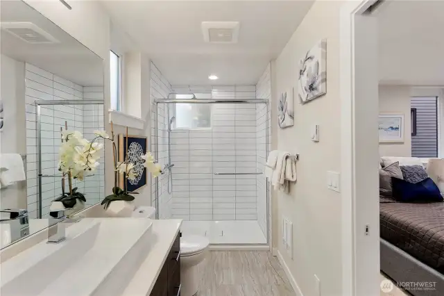 Primary ensuite bathroom with featured trough sink, walk in tiled shower, and built in shelving.