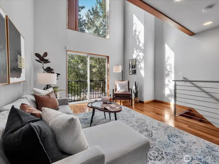 Near-floor-to-ceiling windows and an open stairwell flood this space with natural light.