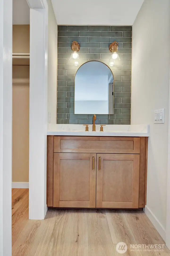 Gorgeous primary bath vanity with tiled wall, new vanity, and brushed gold fixtures!