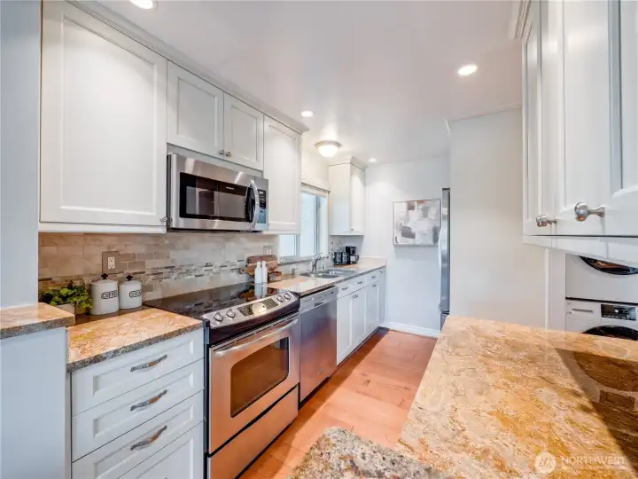 Recessed lighting and crisp white cabinetry create a bright, energizing culinary space that opens directly to your living area.