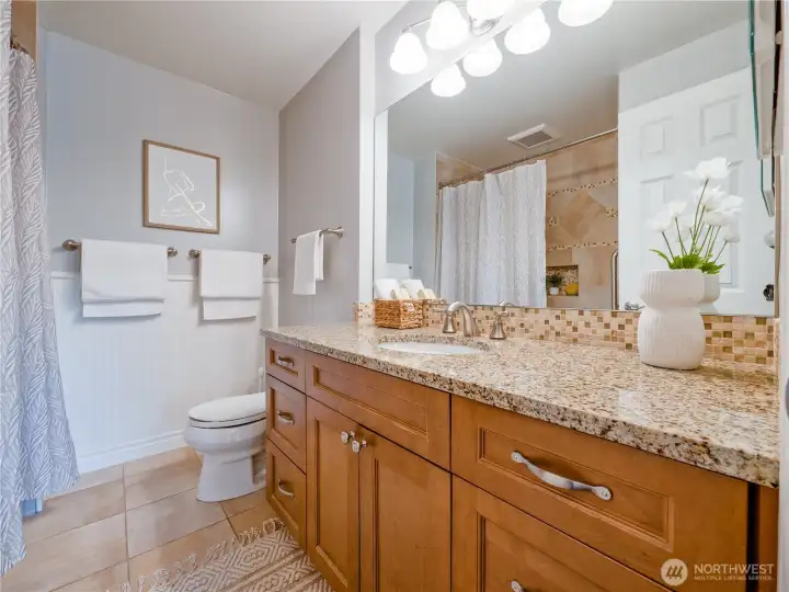 This pristine secondary bath features premium granite and custom mosaic accents, ensuring every guest experiences the high-end finishes they expect.