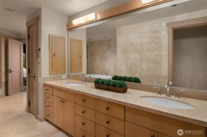 The adjoining bath was designed as a true sanctuary. Travertine marble flooring introduces natural texture and timeless elegance, while custom white oak cabinetry provides warmth and sophistication. A dual-sink vanity offers abundant space, and a cast-iron soaking tub invites moments of relaxation. The spacious walk-in shower and carefully considered finishes create the atmosphere of a luxury spa. Completing the suite is an expansive walk-in closet/dressing room with custom built-ins that balance exceptional organization with refined design. The adjoining bath was designed as a true sanctuary. Travertine marble flooring introduces natural texture and timeless elegance, while custom white oak cabinetry provides warmth and sophistication. A dual-sink vanity offers abundant space, and a cast-iron soaking tub invites moments of relaxation. The spacious walk-in shower and carefully considered finishes create the atmosphere of a luxury spa. Completing the suite is an expansive walk-in closet/dressing room with custom built-ins that balance exceptional organization with refined design.