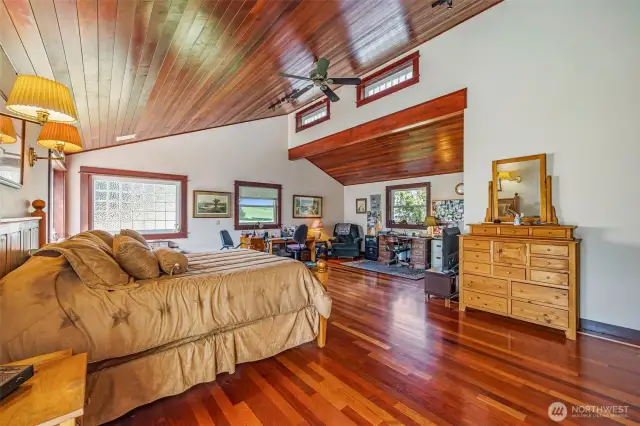This oversized primary suite, added in 1998, is conveniently located on the main level—no stairs! It features a large jetted tub, a versatile sitting area perfect for an office or exercise space, and a walk-in closet with custom organizers. The room is highlighted by Brazilian Cherrywood floors, offering elegance and warmth in this luxurious retreat.