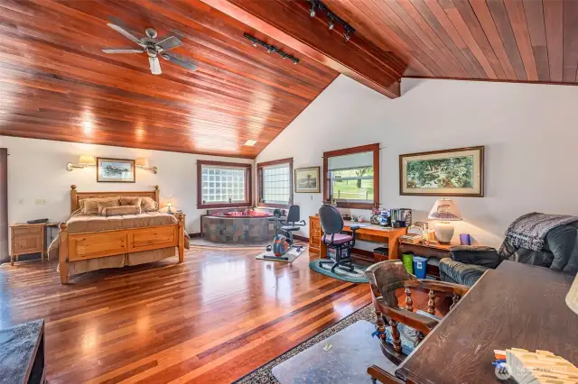 This spacious primary suite includes a large jetted tub, a cozy sitting area perfect for an office or exercise space, and a walk-in closet with built-in organizers. The room is highlighted by Brazilian Cherrywood floors, adding warmth and elegance to this luxurious retreat.