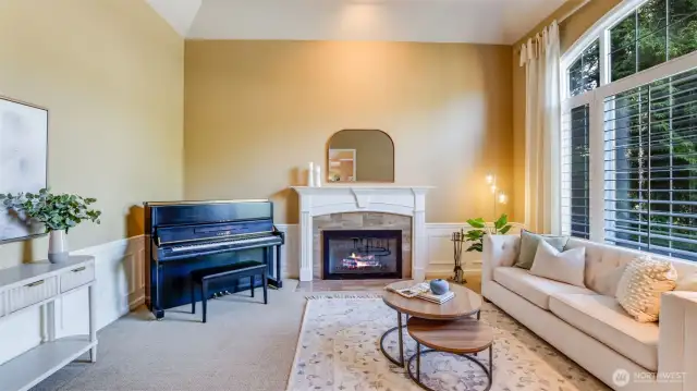 Formal living space off entry elegantly appointed with plantation shutters, marble-surround gas fireplace, wainscot paneling and coffered ceiling