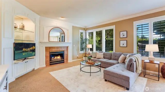 Illuminated family room has so much natural light and includes plantation shutters, gas fireplace, and wood encased detailing