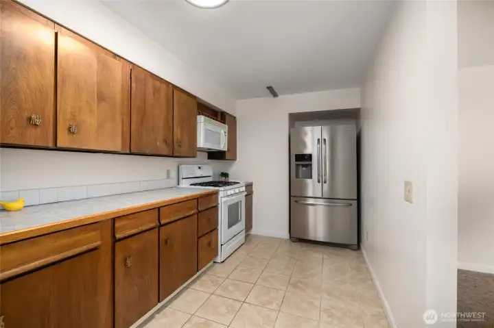 Stainless steel refrigerator and built-in microwave, with lots of counter space.