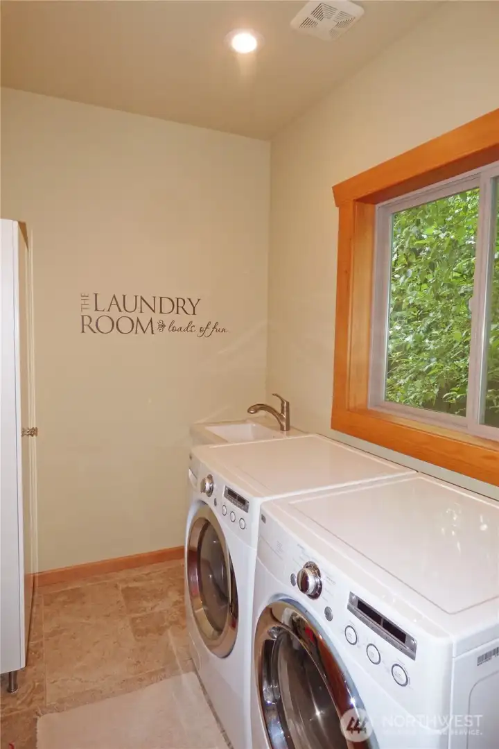 Laundry room with cabinet, sink and washer/dryer (stays with the home). Nice window for fresh air.