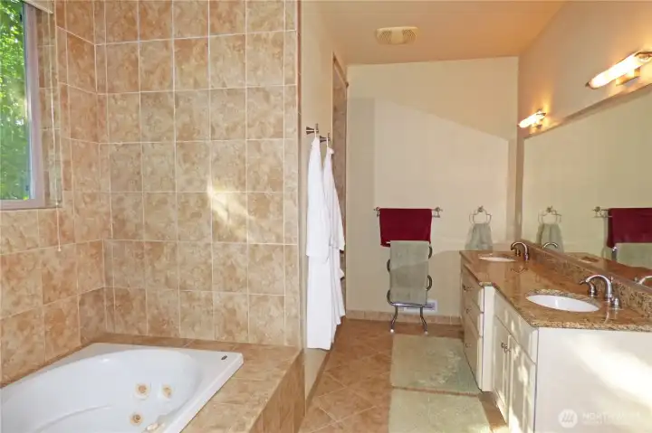 Large primary bathroom. Double sinks, jetted tub and shower just beyond the robes on the left.