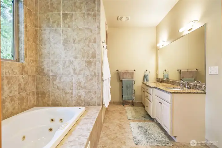 Large  primary bathroom. Double sink, jetted tub and shower just beyond the robes on the left.