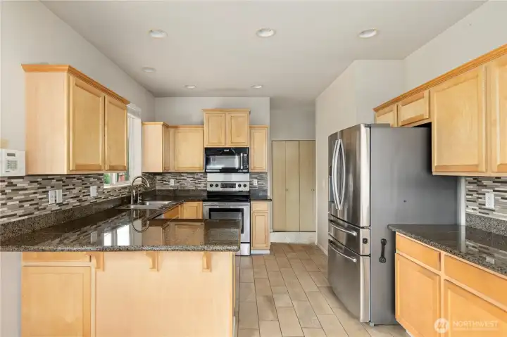 Warm inviting kitchen with stainless steel appliances.  On the other side of the range wall is the utility room and to the right is a half bath and access to the garage.