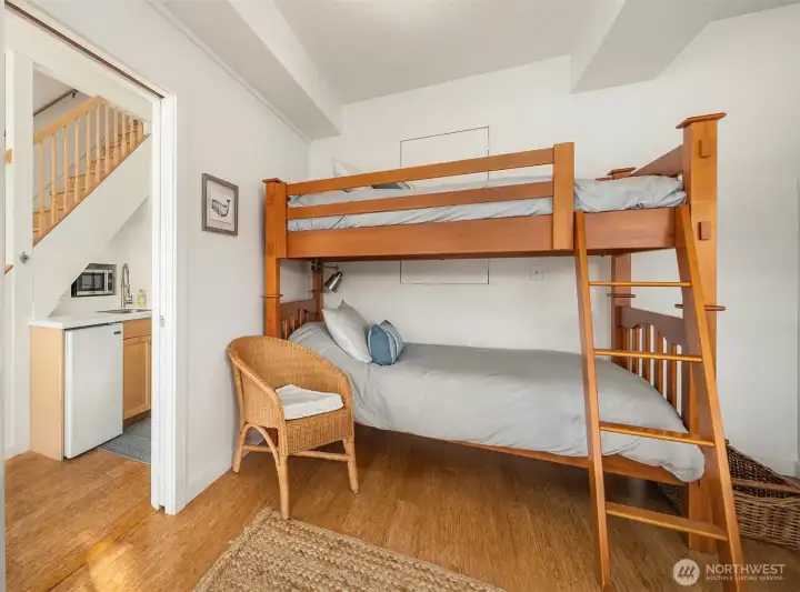 Large flex room downstairs currently used as sleeping quarters with bunk and queen bed with french doors to lower deck with hot tub