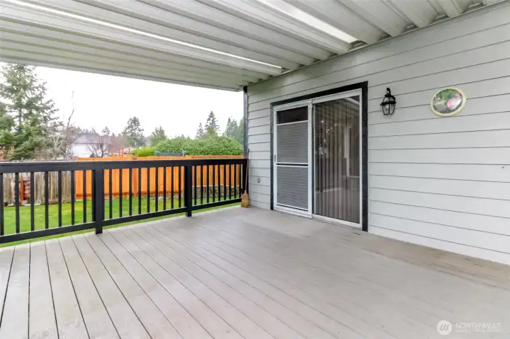 Covered deck with railing looking over to side yard.