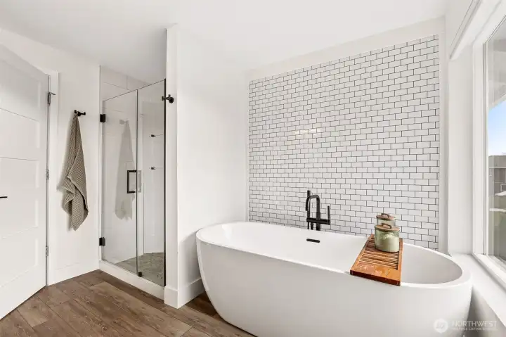 Oversized soaking tub with full tile wall + the full tile shower with a pebble floor- this luxurious bathroom is a must after a hard day at the office.
