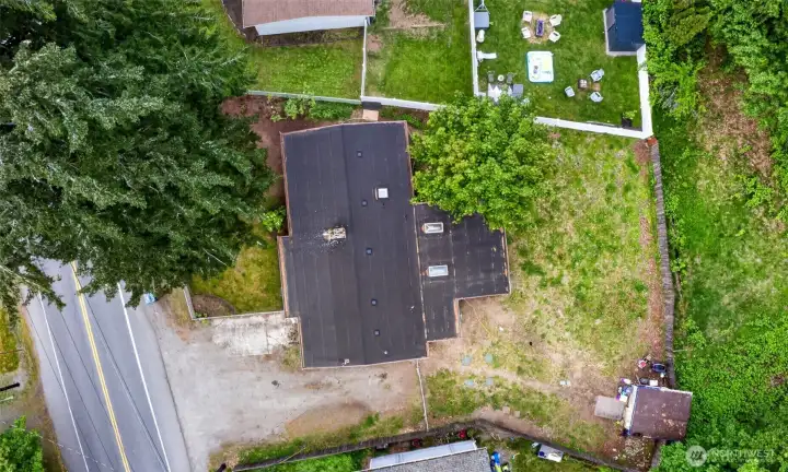 Bird’s-eye view showcasing the impressive lot size and versatile outdoor space this property offers. The expansive backyard provides plenty of room for entertaining, gardening, pets, play areas, or future improvements, while the bordering trees create a natural sense of separation and privacy. From above, you can also see the generous parking area and functional layout of the property, giving the home a spacious feel both inside and out.