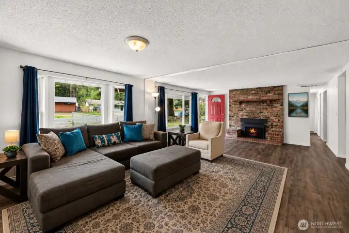 Generous windows and an open layout give this gathering space a bright, airy feel throughout the day. The striking brick fireplace creates a natural focal point, while the oversized living area provides flexibility for entertaining, relaxing, or creating multiple conversation spaces within the home.