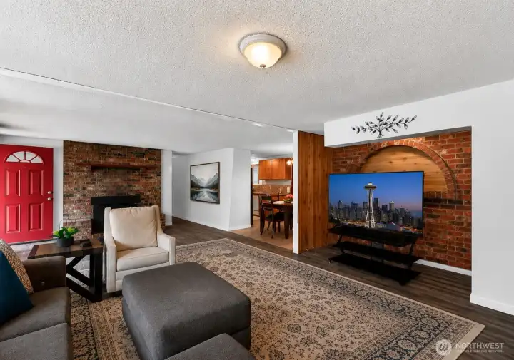 The spacious main living area blends comfort and character with rich flooring, exposed brick accents, and an open-concept design that connects seamlessly to the dining area and kitchen beyond. Distinct architectural details add warmth and personality, while the flexible layout offers plenty of room for gathering, relaxing, or entertaini