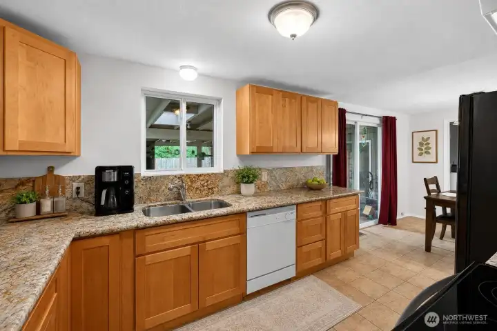 The updated kitchen combines warmth and functionality with rich wood cabinetry, expansive granite countertops, and abundant storage throughout. The efficient U-shaped design provides generous prep space and keeps everything within easy reach for daily cooking and hosting.