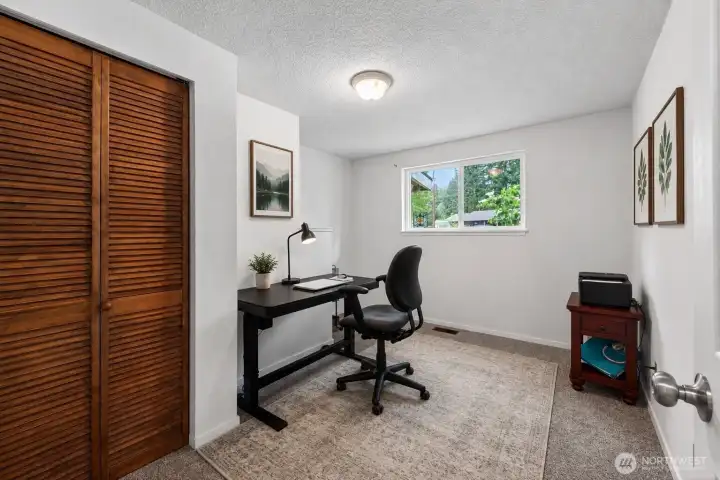 Comfortable third bedroom with a flexible layout perfect for guests, family, or a quiet workspace. The large window brings in natural light and offers peaceful views of the surrounding greenery, while the neutral paint and newer carpet create a bright, clean atmosphere. Ample closet space and a practical floor plan make this room both functional and inviting.