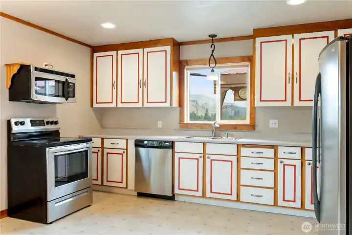 Spacious kitchen with ample cabinetry, stainless steel appliances, and large window bringing in natural light and mountain views.