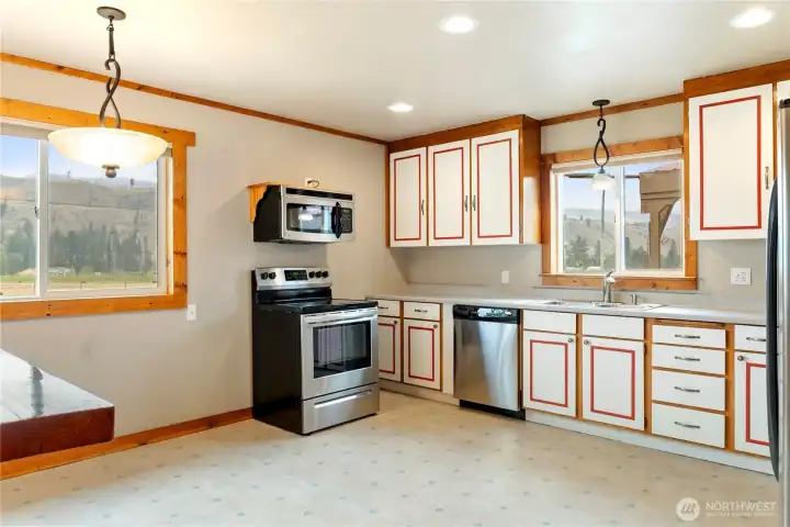 Bright kitchen with ample cabinetry, stainless steel appliances, and window with a view overlooking the mountain view.