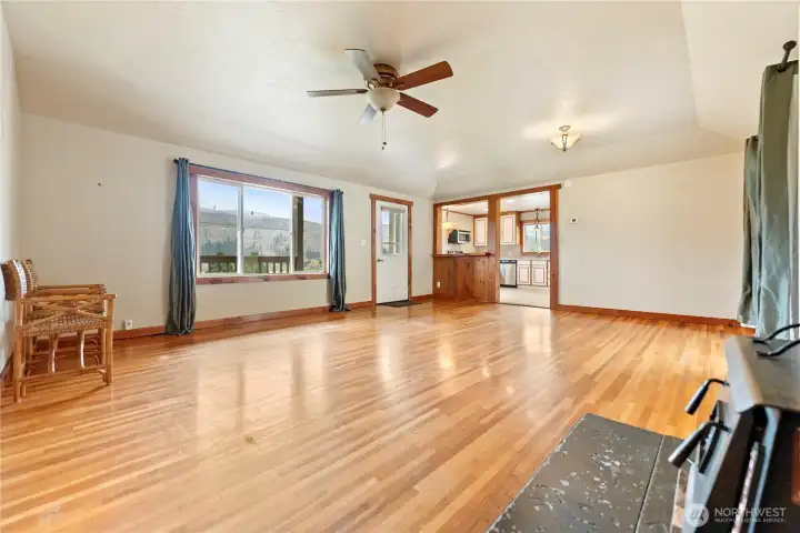 Bright open living space featuring hardwood flooring, big windows with scenic views, and seamless flow into the kitchen.