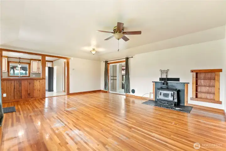 Warm and inviting living room with wood stove, sliding glass doors to the backyard, and natural wood trim accents.