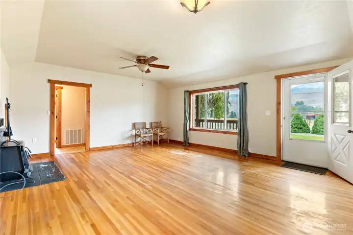 Spacious living room with hardwood floors, ceiling fan, and large picture window bringing in plenty of natural light.