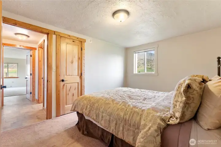 Charming room with hillside views through the window, cozy carpeting underfoot, and a solid wood door with natural trim details.