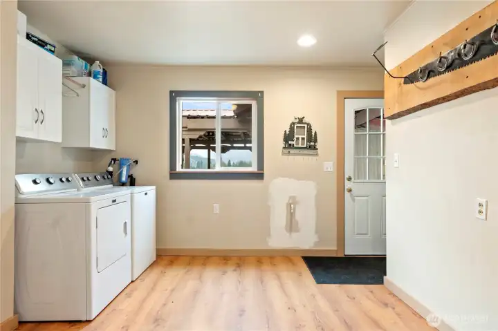 Generous laundry/mudroom with washer and dryer, built-in cabinetry, and plenty of room for storage or workspace. Convenient exterior door access adds functionality.