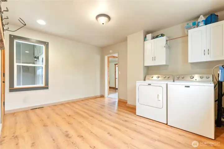 Laundry/mudroom combination with washer, dryer, and upper cabinets. Spacious design allows for organization and household convenience.