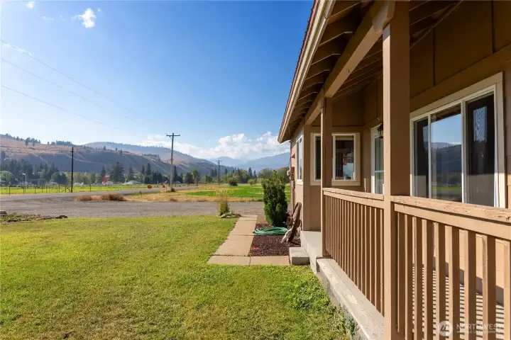 Charming home with metal roof, covered porch, and mature landscaping set against a stunning Methow Valley mountain backdrop.