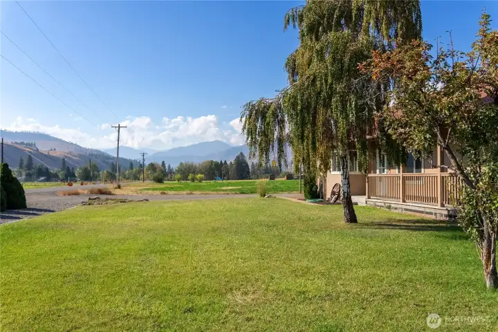 Well-kept front yard with open lawn space, covered porch entry, and panoramic hillside views.