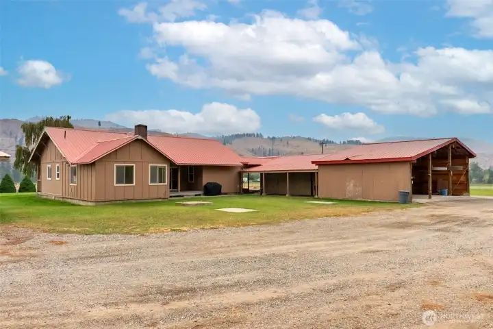 Side view of the home highlighting the large carport and additional outbuildings, ideal for storage or hobbies.