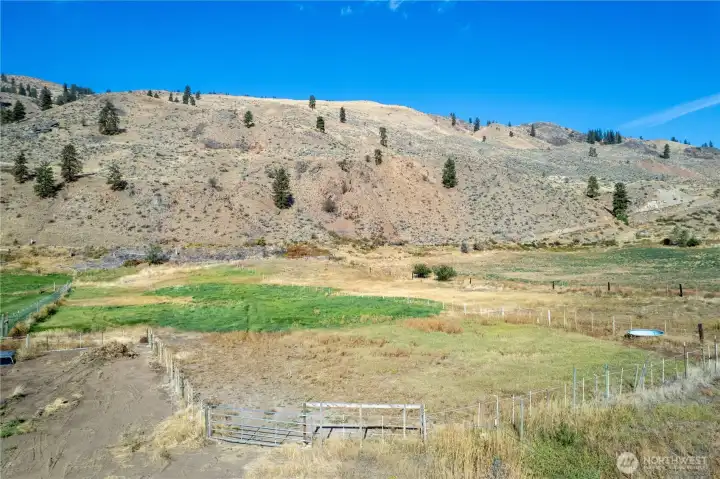 Fenced pasture with open fields, irrigation, ideal for livestock or agricultural use, surrounded by panoramic mountain views.