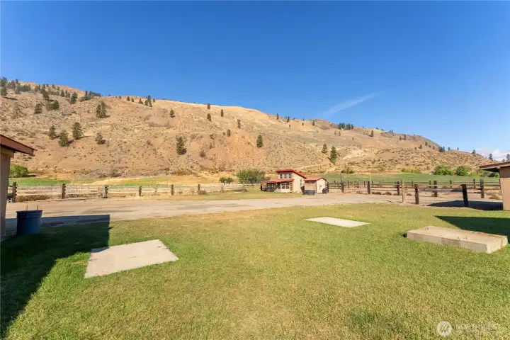 Expansive backyard with open green space, mountain backdrop, and easy access to fenced pastures and outbuildings.