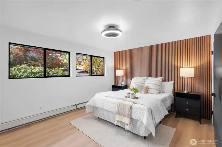 PRIMARY BEDROOM 1 | Located at the back of the home, this is the original primary bedroom, but features modern updates with its beautiful LVP flooring, unique ceiling fan and slatted wall paneling.