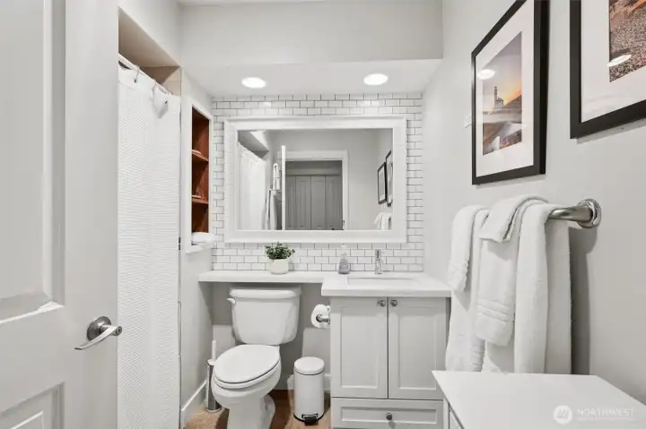 Bright bathroom with upgraded countertops and tile backsplash.