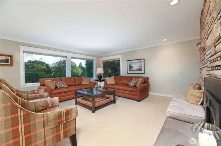 A true Mid-Century living room with a spacious gathering area, dramatic corner wrap windows, and a floor-to-ceiling fireplace that anchors an expansive, conversation-ready seating space.