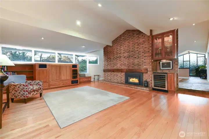 An iconic 1950s family room with a wine bar, hardwood floors, and a dramatic floor-to-ceiling fireplace. Custom built-ins and seamless flow to the dining room and kitchen make this space ideal for gathering.