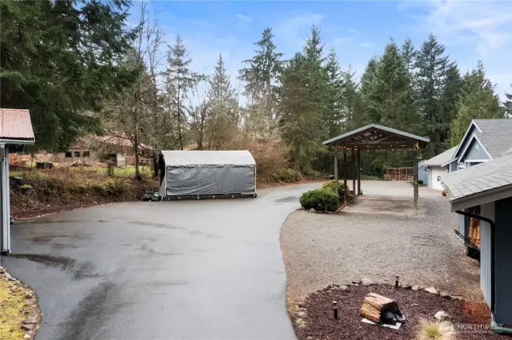 Expansive parking area with covered parking and additional outbuilding space, offering flexibility for vehicles, equipment, or hobbies.