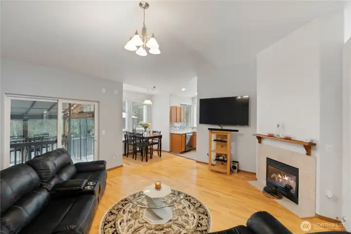 Warm and inviting family room with gas fireplace, hardwood flooring, and sliding glass door leading to the covered outdoor space.