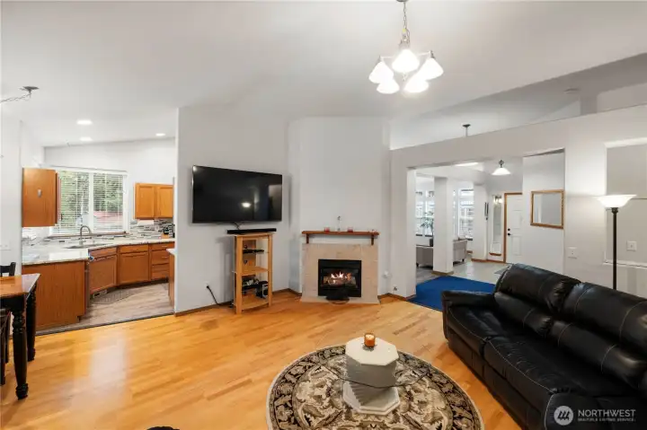 Open living area with hardwood flooring, cozy gas fireplace, and seamless flow into the kitchen.