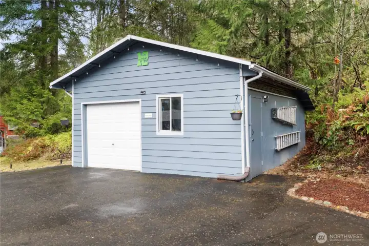 Detached shop with roll-up garage door and paved access, offering excellent space for projects, storage, or hobbies.