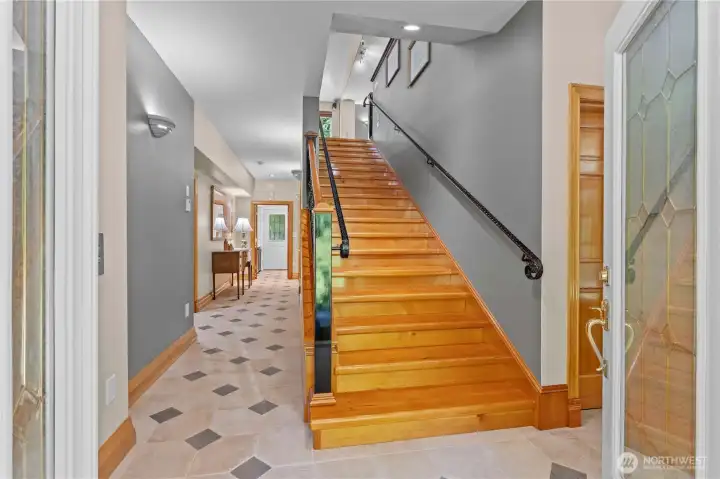 Front entry opens to a solid wood staircase with custom banister and railing. Front entry opens to a solid wood staircase with custom banister and railing.