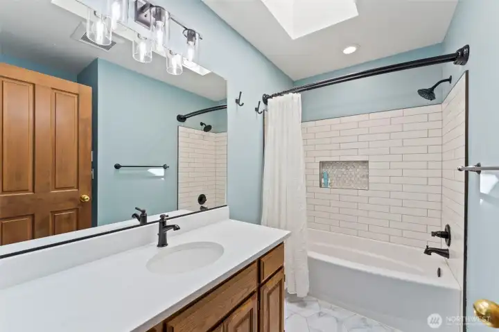 Secondary bathroom updated with quartz counters, heated tile floors and full tile surround.