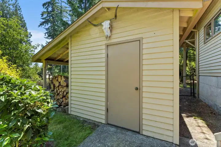 Large shed with shelving, covered mower parking and wood storage.